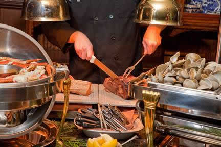 Holidays & Catering 9 Chef cuts a roast on cutting board with other food surrounding the table