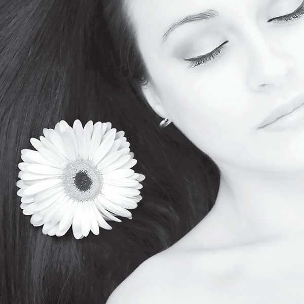 Services 1 Black and white close up of a woman's face. Her hair is spread out next to her with a daisy on top.