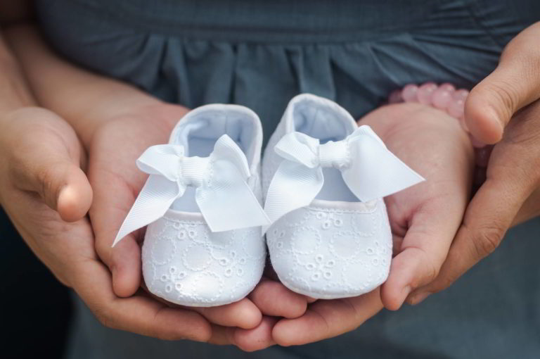 Person holding baby shoes